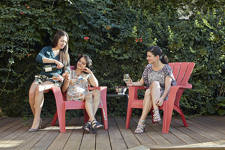 在院子里喝白葡萄酒的成熟女性图片