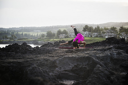 海岸练习平衡瑜伽的年轻女性图片