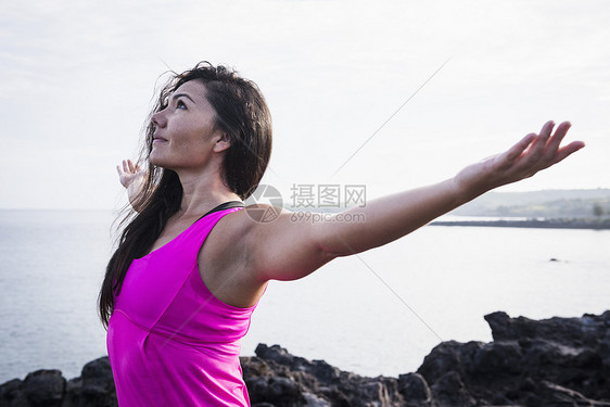 海岸边女子张开双臂练习瑜伽图片