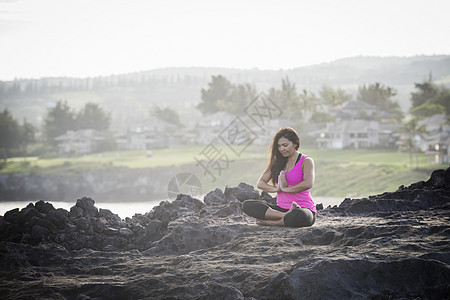 海岸边练习瑜伽的年轻女性图片