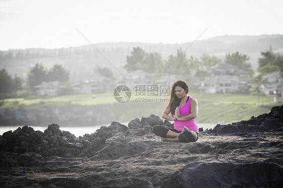 海岸边练习瑜伽的年轻女性图片