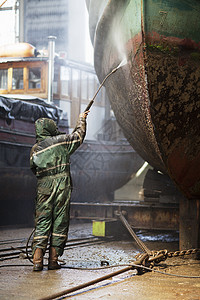 使用高压水管清洁船的工人图片