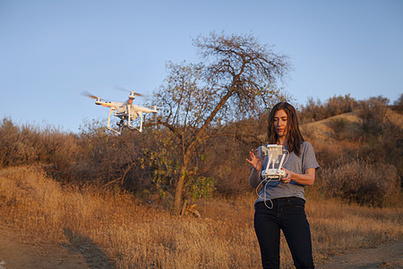 灌木丛飞行无人机的女性航拍手图片