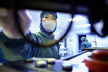 在灵活电子设备工厂清洁室使用机器的女工图片