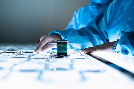 女工在灵活电子设备工厂清洁室的灯盒上检查弹电路图片