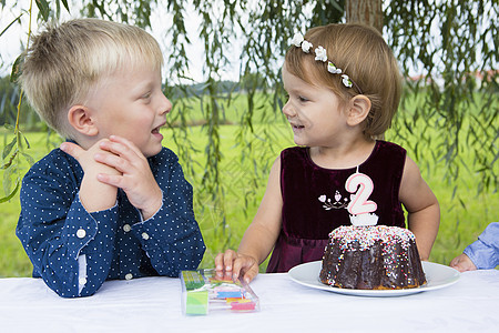男孩和女幼儿生日蛋糕在花园里图片