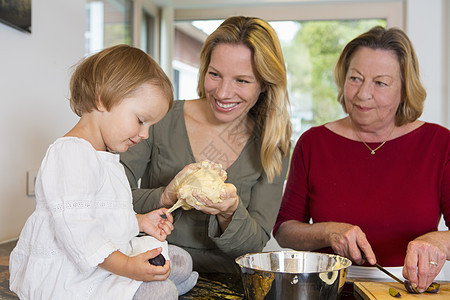 外祖母女儿和幼孙女在厨房准备面粉图片