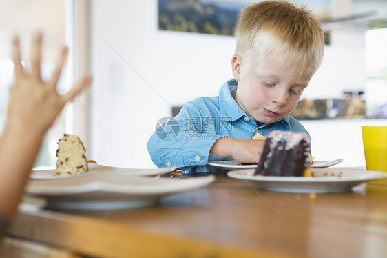 男孩在茶桌上吃蛋糕图片