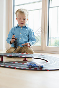 在客厅地板上玩具赛车的男孩图片