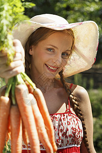 中等成年女子在花园的肖像拿着一堆胡萝卜图片