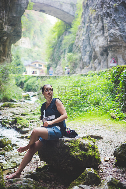 坐在溪流岩山和石桥的上妇女背景意大利加尔达图片