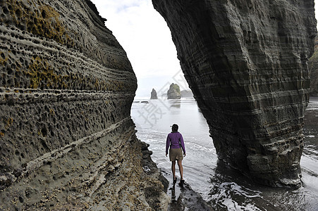 年轻女探索海滩岩层新西兰北岛图片
