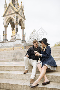 坐在的台阶上使用手机年轻夫妇图片