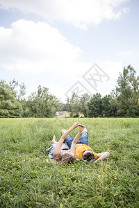 躺在草地上的年轻夫妇使用手机自拍图片