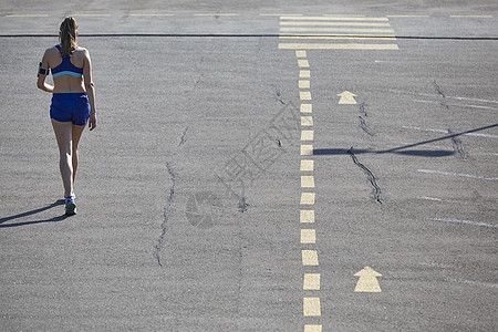 在停车场跑的年轻女步者的近视高清图片