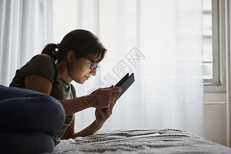 妇女在床上使用数字平板电脑图片