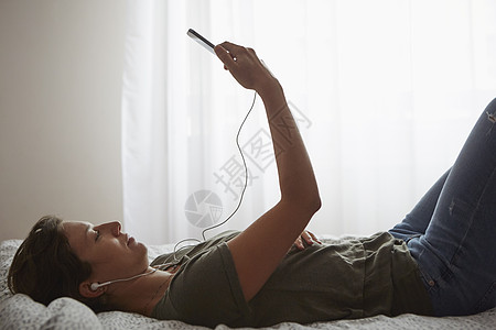 躺床上床上使用智能手机的妇女背景