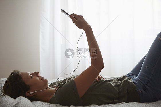 床上使用智能手机的妇女图片