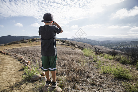 踩在石块上用望远镜眺望的男孩图片