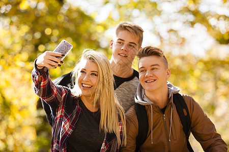 年轻女子在秋林里和两个兄弟自拍图片
