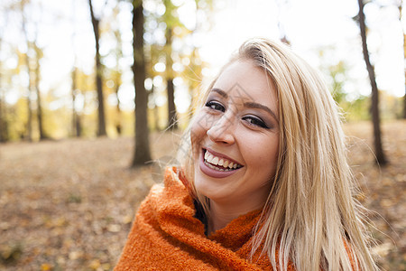 披着毛毯的女性在秋天的树林里图片