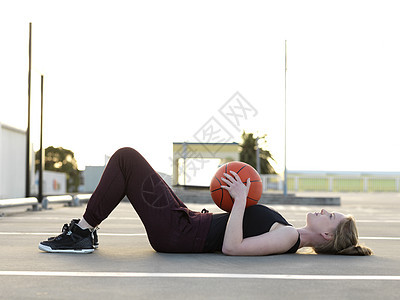 年轻女篮球运动员躺在她背上休息图片