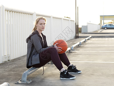 坐在停车场的年轻女篮球运动员图片