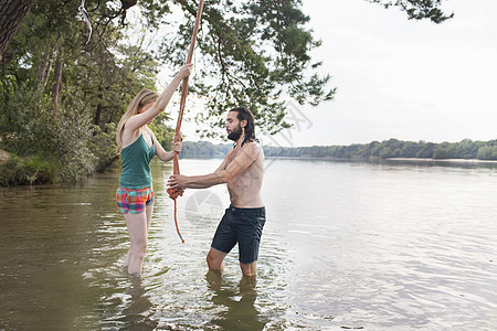 年轻夫妇在湖上玩摇摆的绳子图片