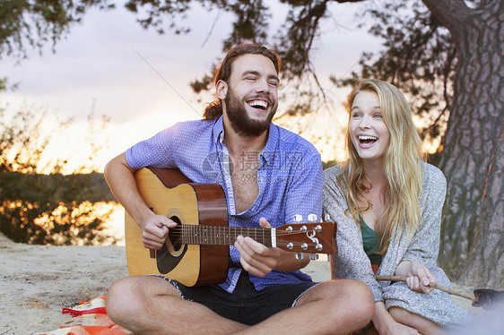 年轻夫妇在湖边弹吉他图片