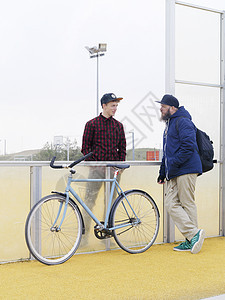 城市骑自行车的人在体育场用栅栏聊天图片