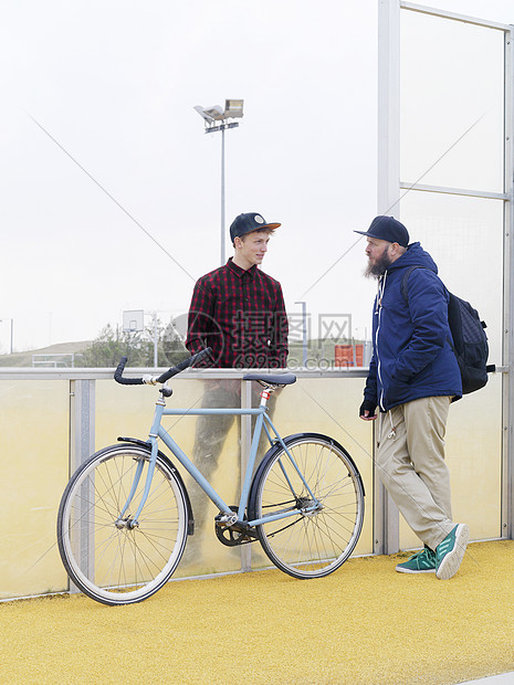 城市骑自行车的人在体育场用栅栏聊天图片
