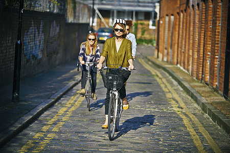 身戴太阳眼镜的妇女将自行车推到路上图片
