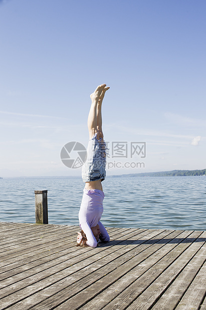 在海边的码头上女人倒立保持瑜伽姿势图片