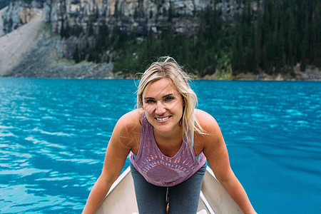 成年女子在莫拉因湖独木舟中望着摄影机微笑加拿大艾伯塔邦夫公园图片