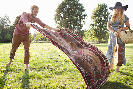 浪漫的年轻夫妇在公园里撒地毯野餐图片