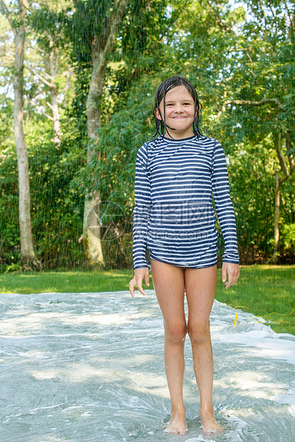 站在花园滑水垫上的年轻女孩图片