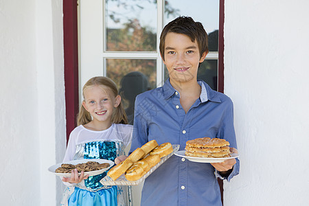 少年男孩和妹在院子上携带蛋糕的图片