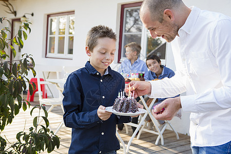 成人中年男子在院上点亮儿生日蛋糕蜡烛图片