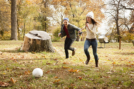 公园里追逐足球的年轻夫妇图片