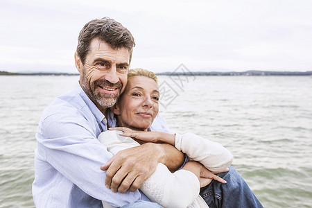 成熟夫妇拥抱在一起坐在码头上图片