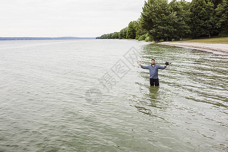 成熟的男子站在海边上举着照相机图片