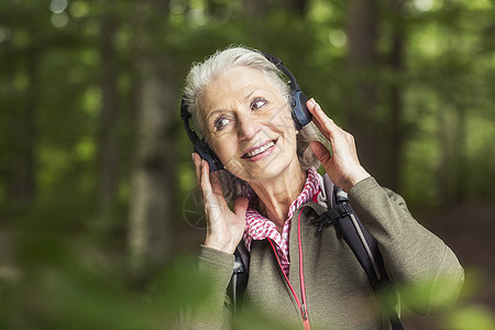 在森林里戴耳机的高龄妇女图片
