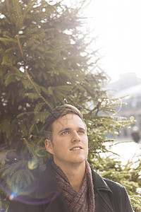 青年男性站在圣诞树前肖像图片