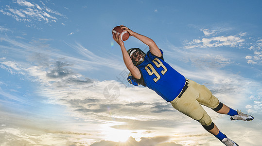 橄榄球运动员在蓝天中捕捉球图片素材