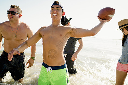 四位成年朋友在美国加利福尼亚州纽波特海滩上玩美式橄榄球图片