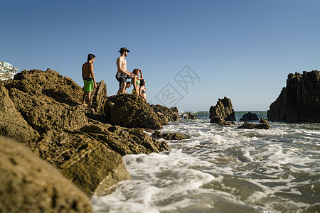 美国加利福尼亚州纽波特海滩探索岩石的年轻朋友图片