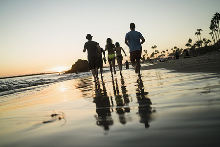 美国加利福尼亚州纽波特海滩日落时在上奔跑的朋友图片