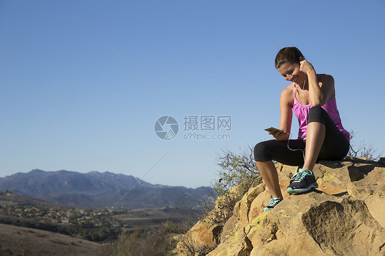 在美国加利福尼亚州千橡树山顶选择智能手机音乐的女选手图片
