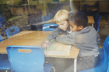 两个男孩在小学教室桌边玩拼图图片