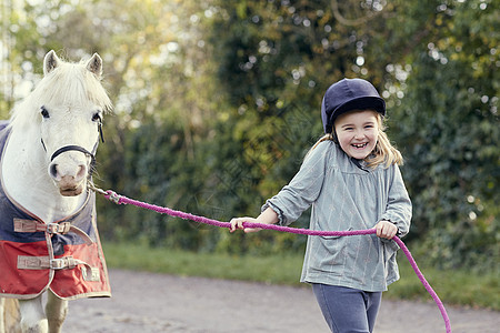 快乐的少女沿车道率领小马图片